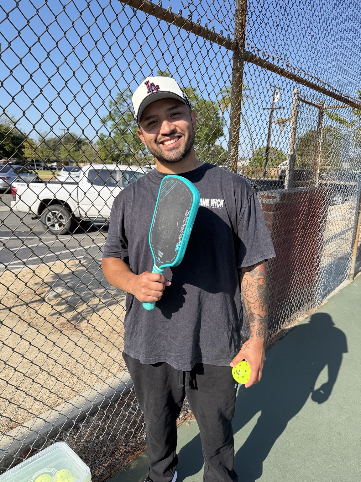 Sean Leyva smiling on the court with his pickleball paddle and ball